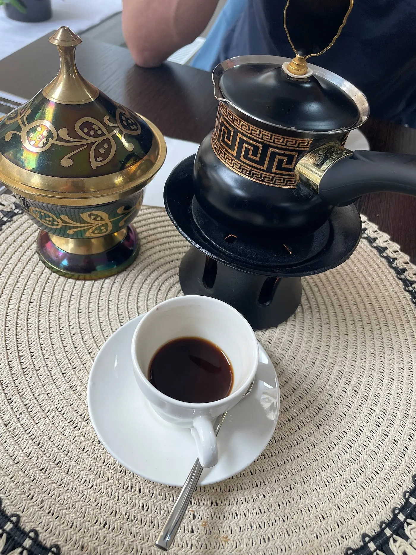 Arabischer Mokka in weißer Tasse, dazu eine schwarz-goldene Kanne auf dem Stövchen und eine verzierte Zuckerdose