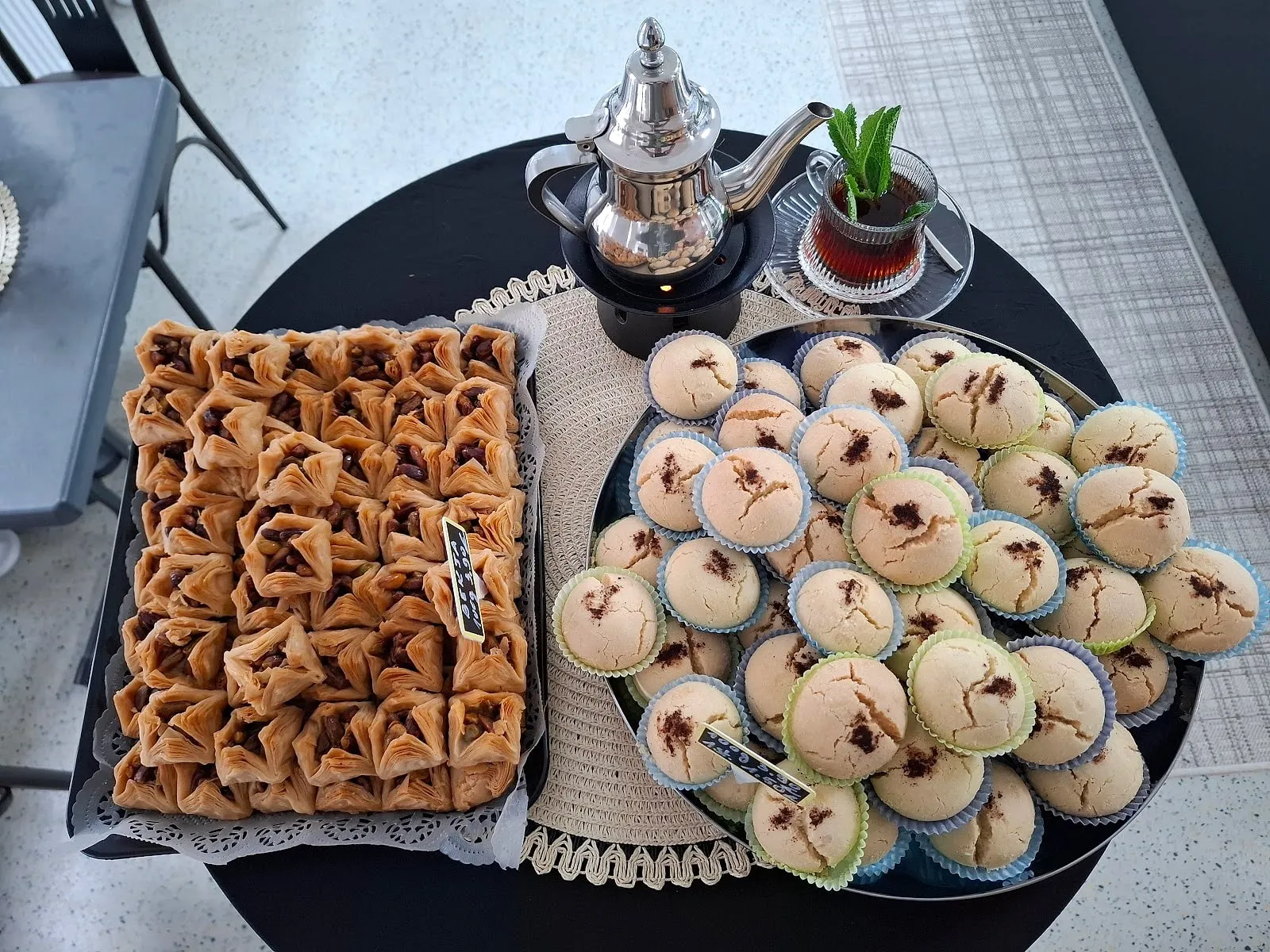 Gedeckter Tisch mit silberner Teekanne, Glas Minztee und einem Tablett Baklava